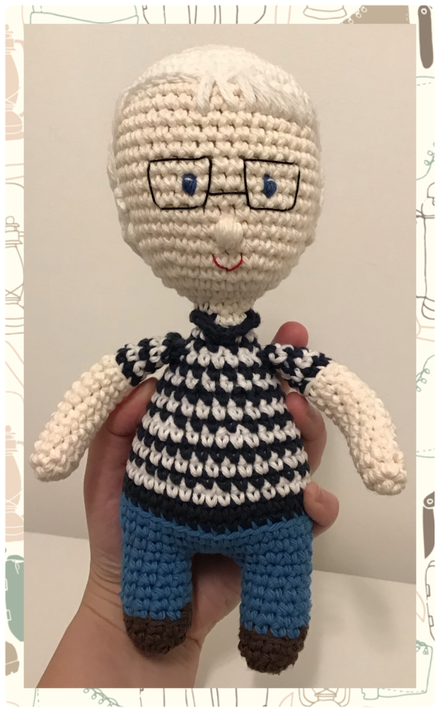 A memorial selfie doll of a papa who has passed. He has white hair and glasses and is wearing his favourite stripped golf shirt